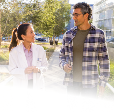 A female UCLA Health physician walking outside of the medical center with a male patient