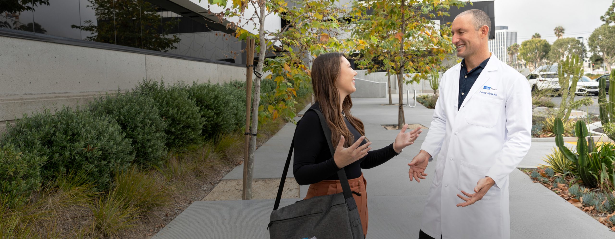 uclahea-cws-foremployees-takecareof A male UCLA Health physician and a female UCLA Health business professional enjoying a conversation outside of a UCLA Health hospital